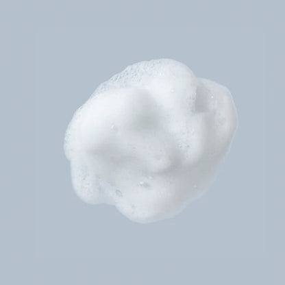 Macro shot of a single dollop of white, creamy Beaver Butter intimate wash foam against a soft grey background.