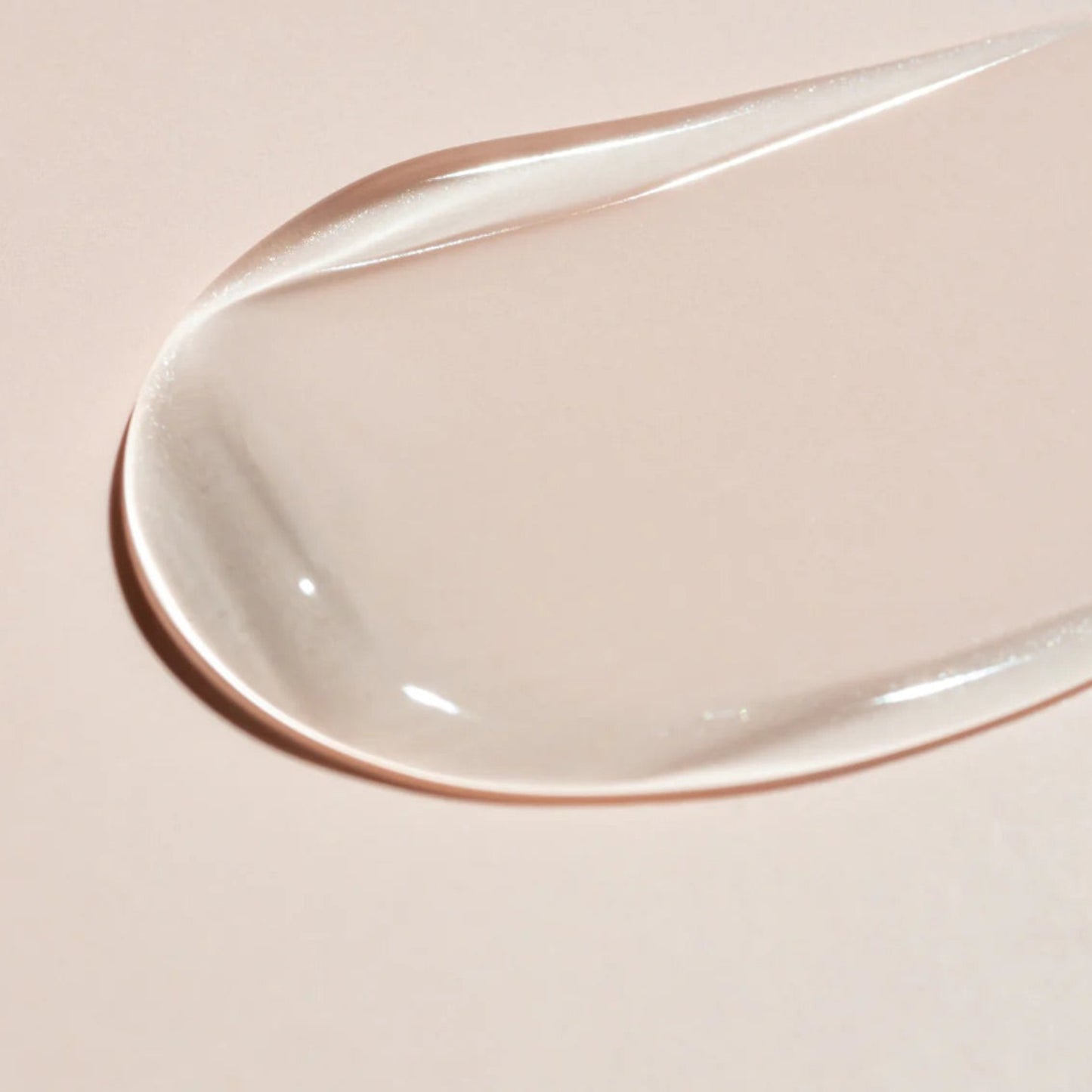 A smooth, translucent swipe of Beaver Butter serum on a neutral pink background, highlighting its exfoliating texture.