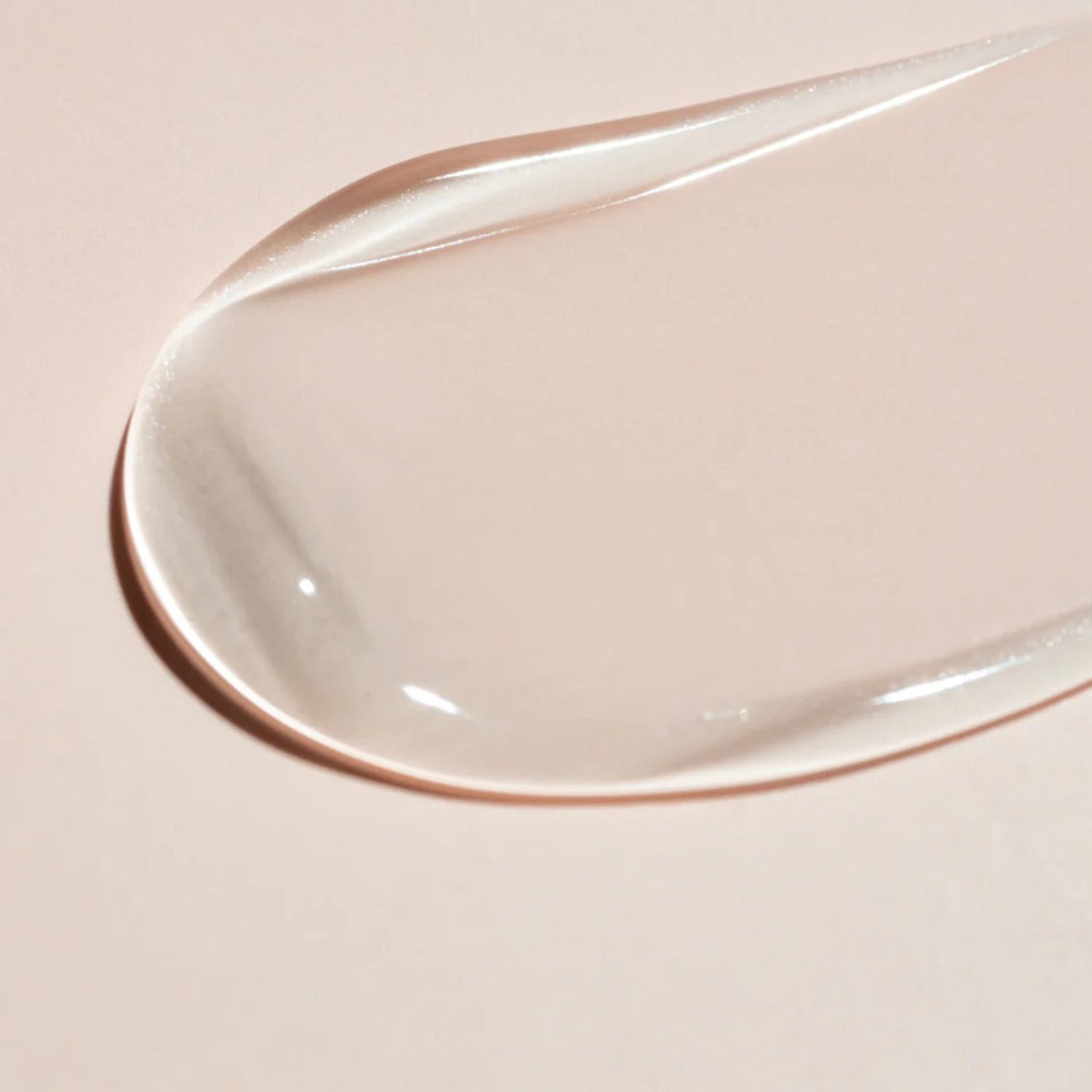 A smooth, translucent swipe of Beaver Butter serum on a neutral pink background, highlighting its exfoliating texture.