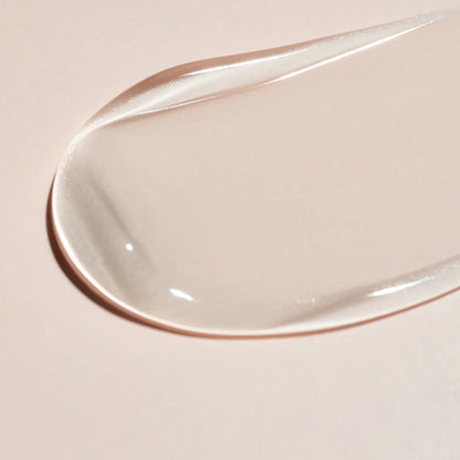 A smooth, translucent swipe of Beaver Butter serum on a neutral pink background, highlighting its exfoliating texture.