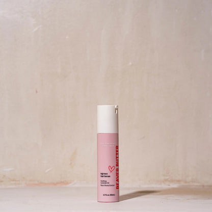 The pink Beaver Butter Ingrown Hair Serum bottle standing against a textured wall, showcasing the "Love Your Beaver" branding.