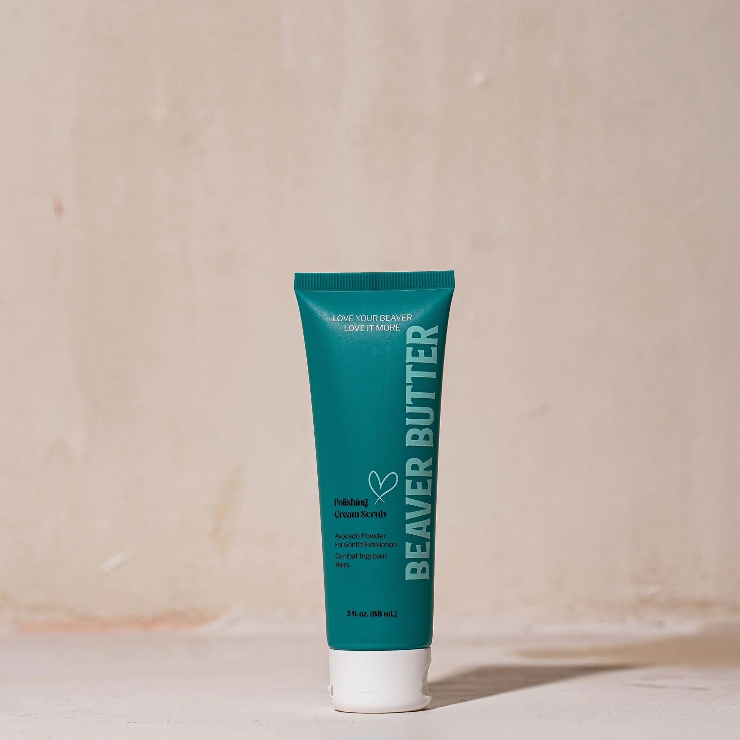 A 3 fl. oz. (88 mL) travel-sized teal tube of Beaver Butter Polishing Cream Scrub standing upright on a minimalist surface against a warm, neutral-toned background.