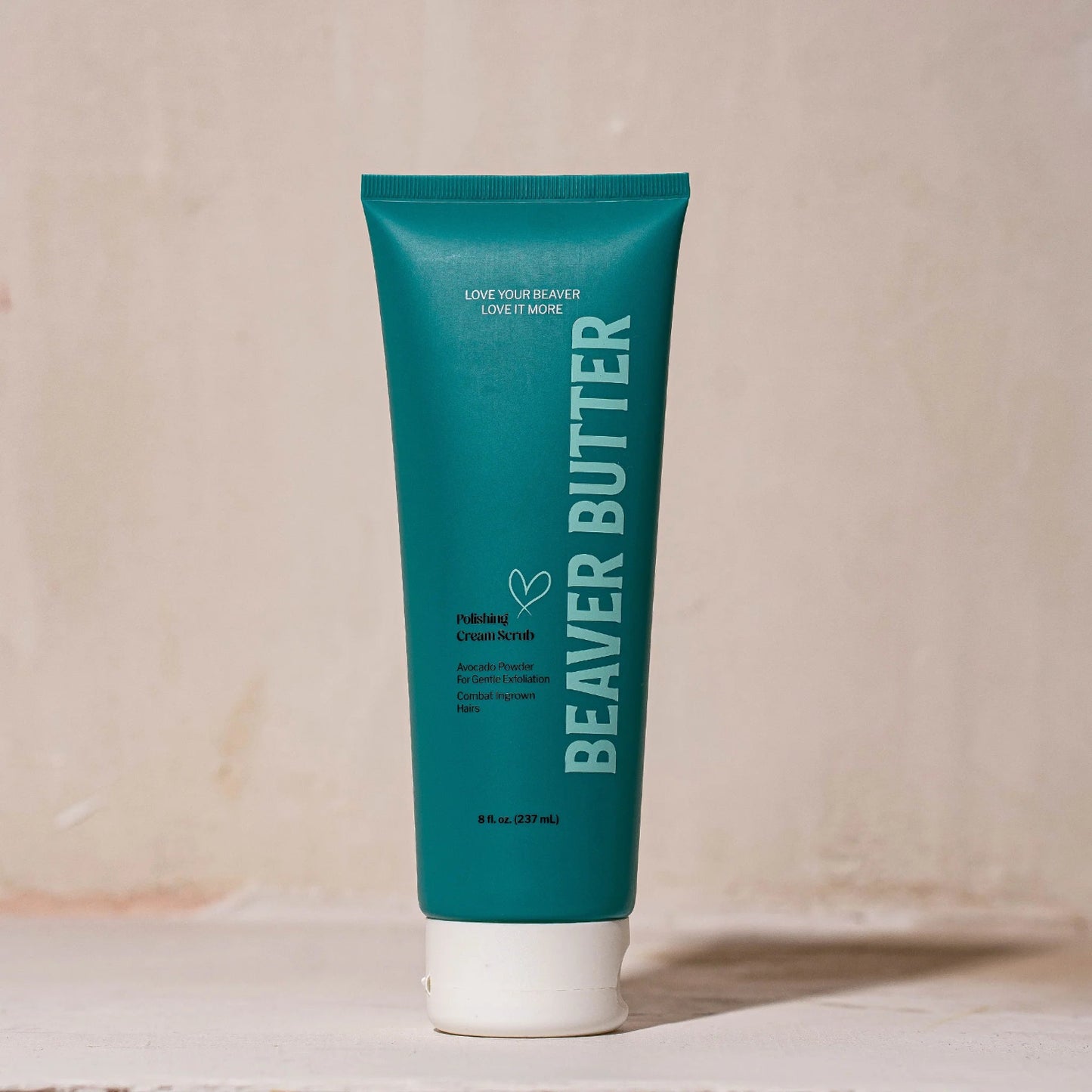 Full-sized 8 fl. oz. (237 mL) tube of Beaver Butter Polishing Cream Scrub standing upright against a textured, earthy-coloured plaster wall.