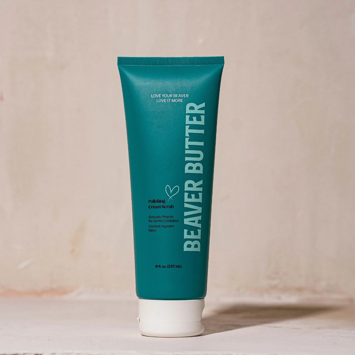 Full-sized 8 fl. oz. (237 mL) tube of Beaver Butter Polishing Cream Scrub standing upright against a textured, earthy-coloured plaster wall.