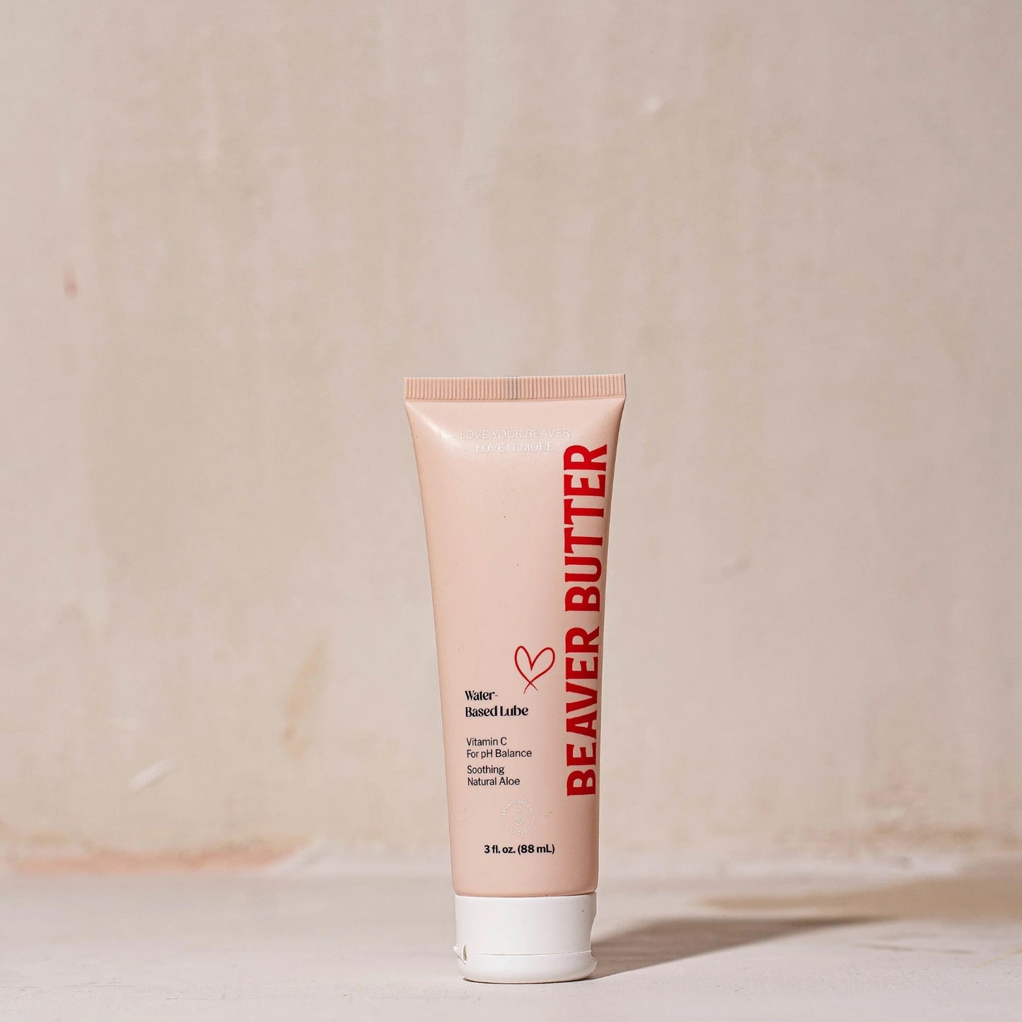Front view of the 88 mL / 3 oz Beaver Butter personal lubricant tube featuring minimalist peach packaging and red typography.