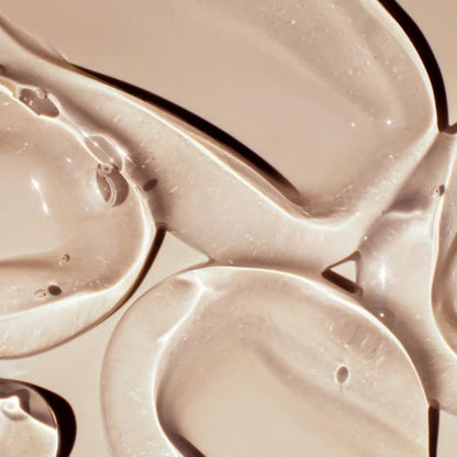 Overhead shot of multiple thick, clear swirls of Beaver Butter water-based lubricant on a neutral tan surface.