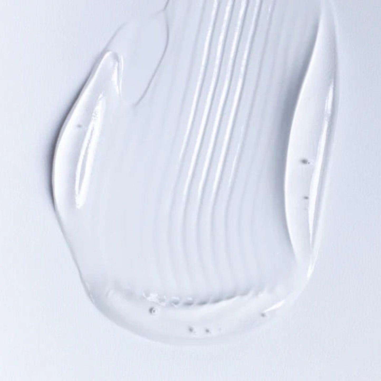 A close-up of a viscous, transparent personal lubricant gel on a white background showing smooth, hydrating ridges.
