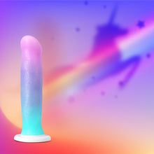 Load image into Gallery viewer, Bottom side of the blush Avant Lucky Dildo giving off a unicorn shadow with a rainbow coming out from behind the product, all on a gradient background.