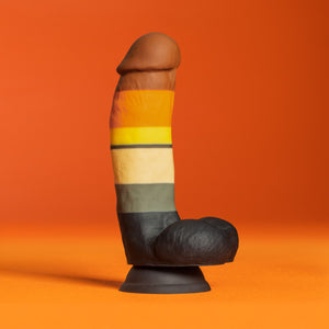 Side view of the blush Avant Pride Bear Realistic Dildo, placed on its suction cup, with an orange background.