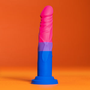 Side view of the blush Avant Pride Love Dildo, placed on its suction cup, with an orange background.