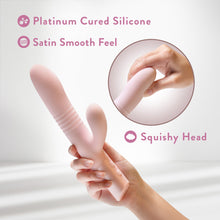 Charger l&#39;image dans la galerie, A woman&#39;s hand is holding the Blush Fraya Thrusting Rabbit, and slightly above it is a separate image in a circle of a woman&#39;s hand squishing the head of the product. Feature icons for: Platinum cured silicone; Satin smooth feel; Squishy head.