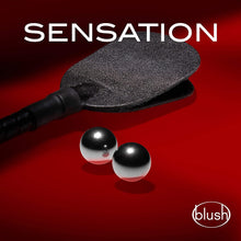 Load image into Gallery viewer, An image of a paddle looking object with the blush B Yours Gleam Ben Wa Balls, on a red background. On the top is written sensation, and on bottom right is the blush logo.