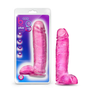 On left side of image is product packaging. On packaging (top to bottom): b yours plus logo, by blush, Big n' Bulky, text bubble "10.5 inch dildo", text bubble "I'm transparent", product feature icons for: Ultra soft realistic feel; Fragrance free; Harness compatible; Strong suction cup base, on the bottom left corner is an icon for Laboratory certified, body safe, and on right side of packaging is an image of product. Beside is product blush B Yours Plus Big n' Bulky 10.5 Inch Dildo.