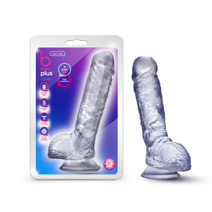 On right side of image is product packaging. On packaging (top to bottom): b yours plus logo, by blush, icon features for: Ultra soft realistic feel; Fragrance free; Harness compatible; Strong suction cup base, text bubbles: "Hearty N' Hefty"; "9 Inch Dildo"; "I'm transparent" (pointing to product). In middle is image of product, and on bottom right is icon for Laboratory tested - body safe. On right side of image is product blush B Yours Plus Heart N' Hefty 9 Inch Dildo, placed on its suction cup.