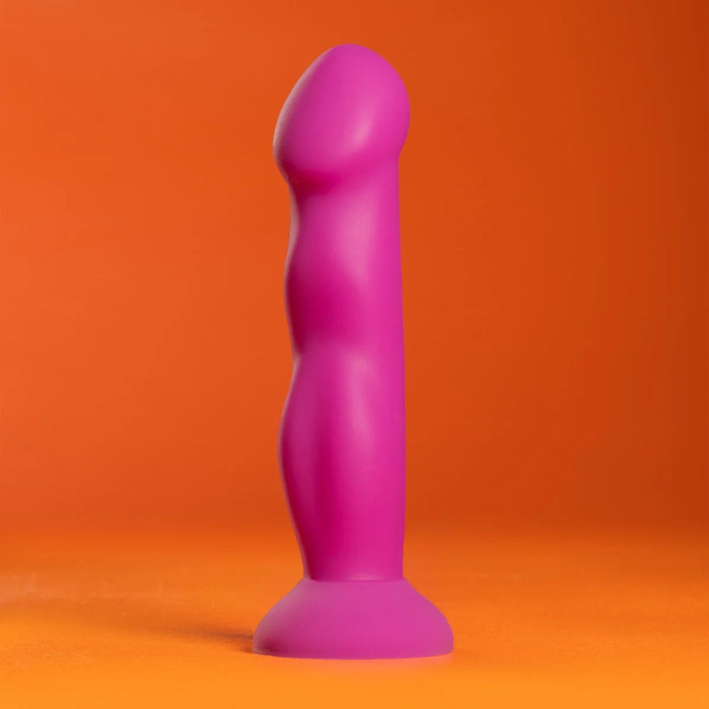 Profile studio shot of the purple Avant Suko silicone dildo standing on a vibrant orange background.