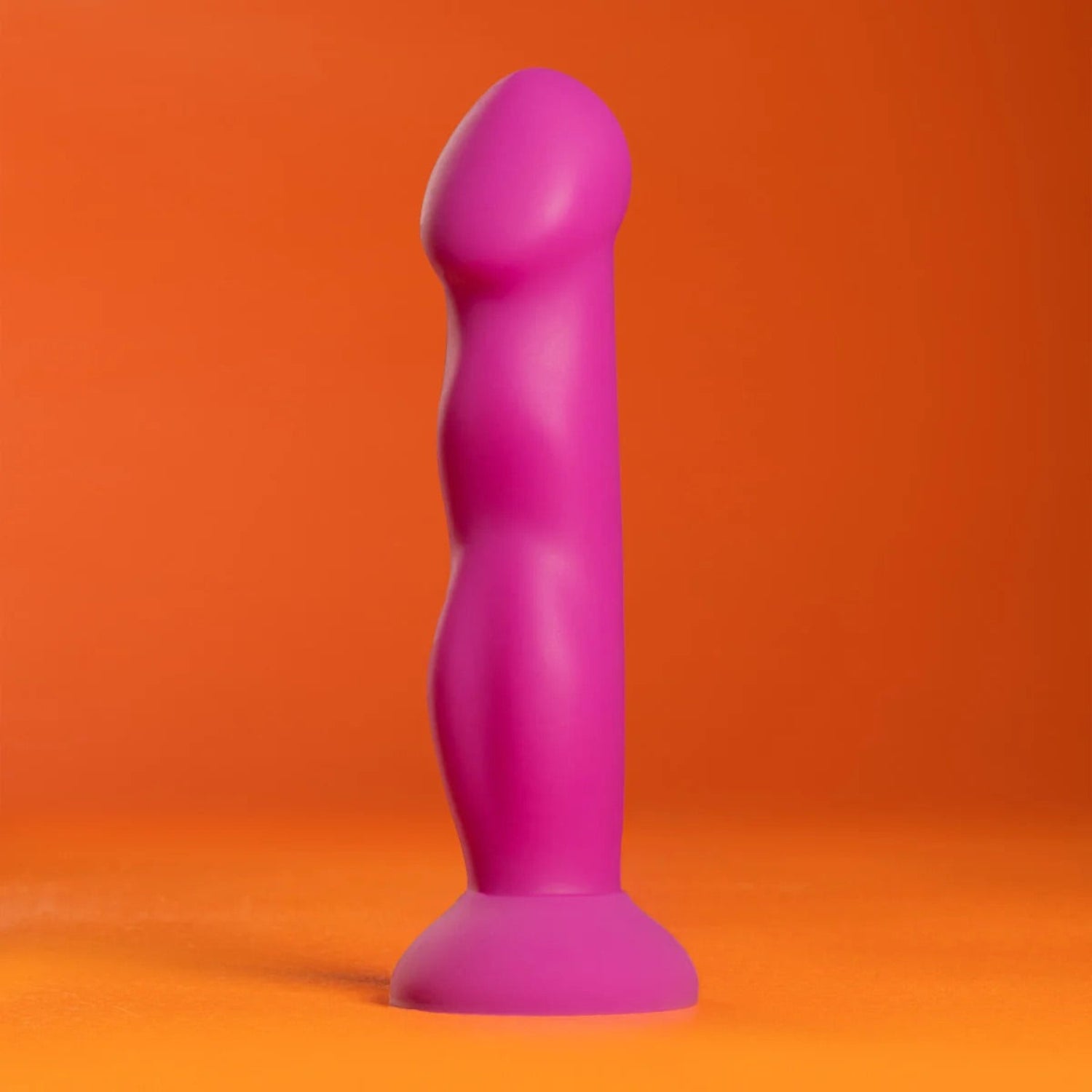 Profile studio shot of the purple Avant Suko silicone dildo standing on a vibrant orange background.