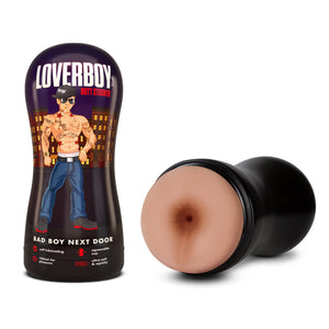 On the left side of the image is the cover of the stroker stood up from the bottom. On the cover is the Loverboy logo, "Butt stroker", with an illustrated shirtless male figure, with a backdrop of apartment buildings, product name: Bad Boy Next Door, feature icons for: Self lubricating; Squeezable cup; Ribbed for pleasure; ultra-soft & squishy. Beside is a front view of the stroker, placed on its side.