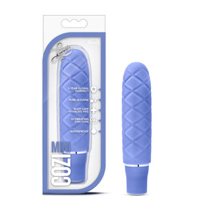 On the left side of the image is the Periwinkle variant product packaging. On the packaging is the Luxe logo, product feature icons for: 5 year global warranty; Pure silicone; Body safe phthalate free; 10 vibrating functions; waterproof, product name: Cozi mini, and the product inside fully visible through clear packaging. Beside the packaging, is the product blush Luxe Cozi Mini Periwinkle Vibrator, standing up on its base.