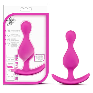 On the left side of the image is the product packaging. On the packaging is the Luxe logo, product feature icons for: Pure silicone; Body safe phthalate free; Smooth satin finish; Flexible for pleasing, extended comfort, ez-handle conforms to you, product name: Explore Silicone Anal Plug, and the product inside fully visible through clear packaging. Beside the package is the product blush Luxe Explore Silicone Anal Plug, stood up on its handle.