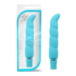 On the left side of the image is the aqua variant product packaging. On the packaging is the Luxe & blush logos, product feature icons for: Pure silicone; 2 vibrating speeds; waterproof, on the bottom left is the product name: Purity G, and the product fully visible inside the packaging. Beside the packaging is the product, blush Logo Purity G aqua Vibrator.