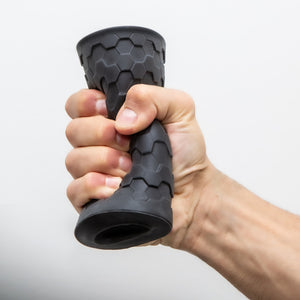 A male hand is squeezing the bush M For Men Hekx Platinum-Cured Silicone Stroker, demonstrating how squishy the product is.
