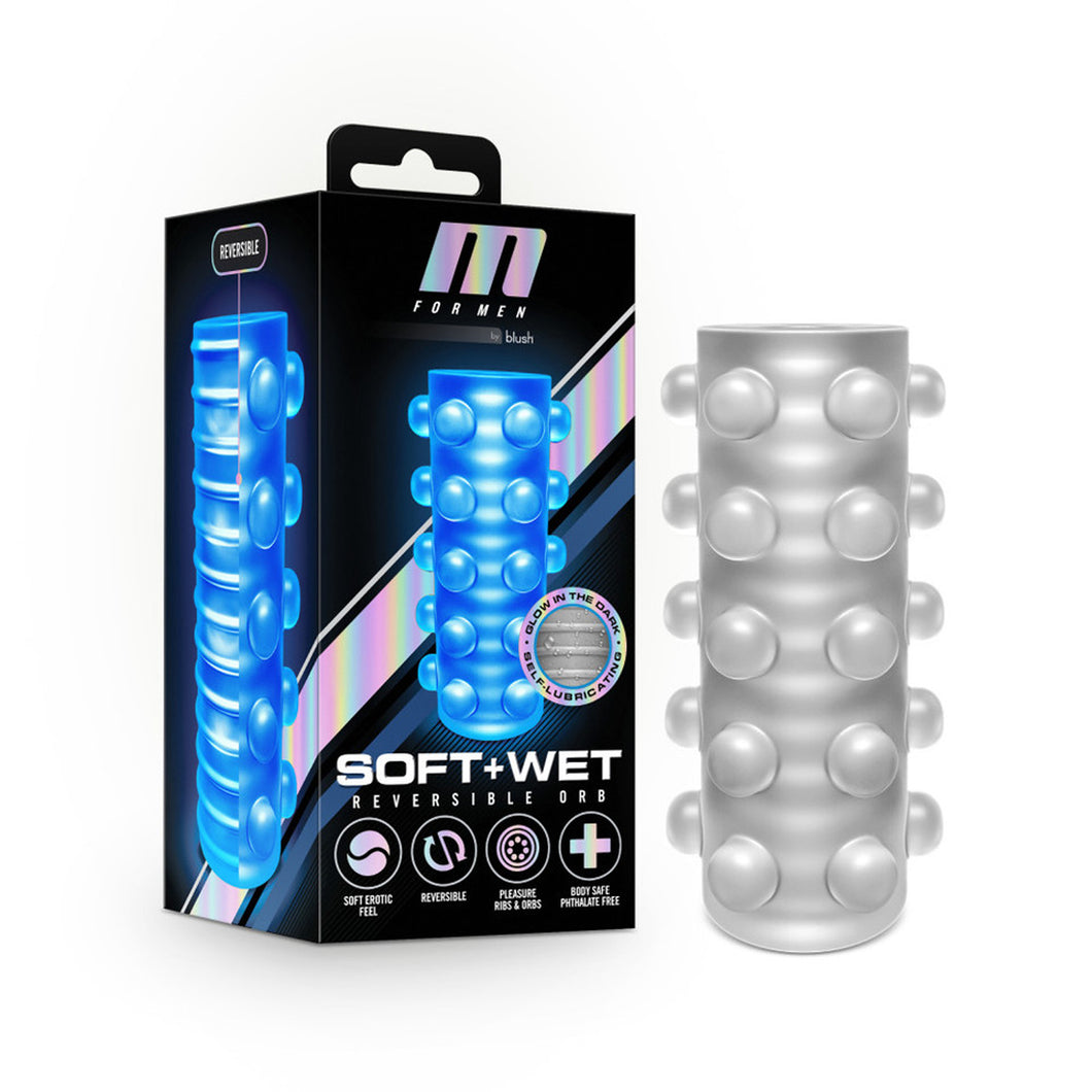 Left side of image is product packaging. On top left side of package is written: Reversible, that's pointing to 2 sided stroker, split at middle. Front package M for Men by blush logo, with illustrated image of stroker glowing in dark, an image showing ribbed texture, captioned: Glow in the dark; Self-Lubricating, Product name: Soft + Wet Reversible Orb, and product feature icons for: Soft erotic feel; Reversible; Pleasure Ribs & Orbs; Body safe phthalate free. Beside packaging is the product.