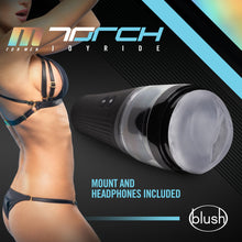 Load image into Gallery viewer, Side view picture of a woman wearing lingerie, with both hands in the air, and the blush M For Men Torch Joyride Male Masturbator beside her. On the top is the M for Men logo, and product name: Torch Joyride, &quot;Mount and headphones included&quot;, and on bottom right is the blush logo.