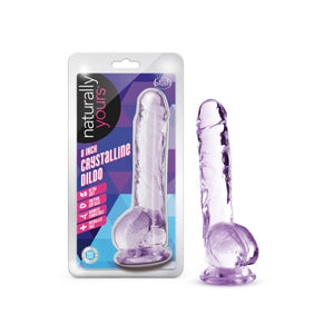 On the left side of the image is the product packaging. On the packaging from the top are the naturally yours & blush logos, product name: 8 Inch Crystalline Dildo, product feature icons for: Ultra Soft; Suction cup base; Harness compatible; Phthalate free; Laboratory certified - body safe, and on the right side is the product inside visible through clear packaging. Beside the packaging is the product, standing on its suction cup base.
