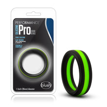 Load image into Gallery viewer, On the left side of the image is the packaging. On the packaging is the Performance logo, product name: Silicone Pro Cock Ring, product features: Pure silicone; Flat design for a comfortable &amp; secure fit; Strong &amp; stretchy, in the middle is the product inside visible through clear packaging, at the bottom &quot;1.5inch (38mm) diameter&quot; and the blush logo in the right corner. Beside the packaging is the blush Performance Silicone Pro black/green Cock Ring.