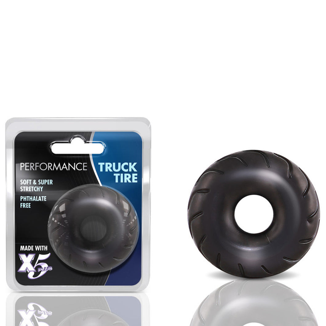 On the left side of the image is the packaging. On the packaging is the Performance logo, product name: Truck Tire, product features: Soft & super stretchy; Phthalate free; Made with X5 Plus, and in the middle is the product visible through clear packaging. Beside the packaging is the product, blush Performance Truck Tire Cock Ring standing up.