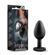 Charger l&#39;image dans la galerie, On the left side of the image is the product packaging. On the packaging is a background image of a female&#39;s backside wearing lingerie, and a photo of the product with the base facing up, product features: embedded with a beautiful gem; Perfect for more advanced players; Tapered tip for easy entry; Made of pure silicone; Satin smooth; 3&quot; length, Temptasia logo, and product name: Bling Plug - Small. Beside packaging is the product standing on its base.