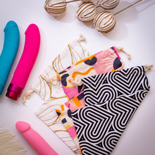 Load image into Gallery viewer, An image of the 3 style variants of the blush The Collection Cotton Toy Bag laying on top of each other and folded at an angle from top to bottom: Bomba, Burst, and Embrace. Laying beside the Toy Bags are 3 vibrators.