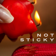 Load image into Gallery viewer, A closeup of a female&#39;s hand dripping the wax from a lit up blush Temptasia Fox Drip Candle on to a red fabric, with caption text in the bottom right: Not sticky.