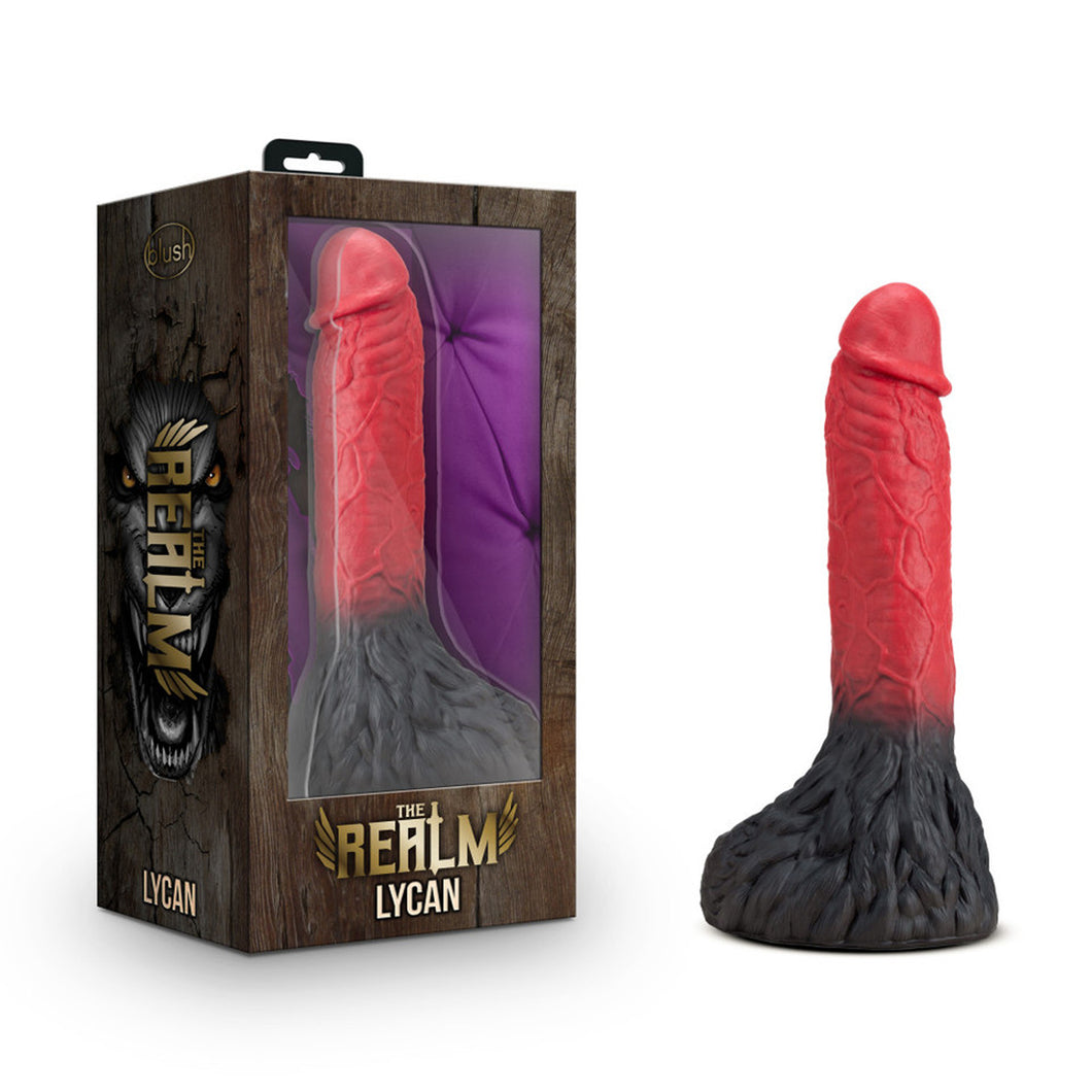 On the left side of the image is the product packaging. On the left side of the product packaging is the Realm logo, and product name: Lycan. On the front of packaging is the product visible through clear packaging, below is The Realm logo, and product name: Lycan. Beside the packaging is the Dildo standing on its base.