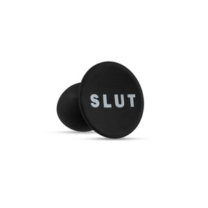 Bottom side of the blush Temptasia Slut Plug, showing the word "Slut" written on the bottom of the base.