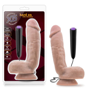 On the left side of the image is the product packaging. On the packaging is the X5 logo, product name: hard on with vibration, product features icons for: 10 vibration functions; Lab certified body safe; Fragrance free; Soft realistic feel; Harness compatible; Suction Cup; Phthalate free, and the product inside fully visible through clear packaging. Beside the packaging is the product standing on its suction cup base, and the remote controller hovering behind and to the right.