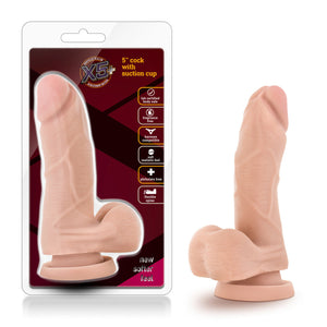 On the left side of the image is the product packaging. The packaging shows the product fully visible through clear packaging, X5 Plus logo, inside the logo has a slogan: Unrivaled realism - Revolutionary material, product name: 5" Cock with Suction Cup, product feature icons for: Lab certified - Body safe; Fragrance free; Harness compatible; Soft realistic feel; Phthalate free; Flexible spine, and at the bottom "New softer feel". Beside the packaging is the product standing on its suction cup.