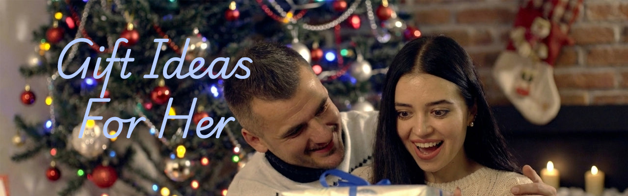 Man and woman looking at a gift with Christmas tree and decorations in the background. On the left side of the banner shows text "Gift Ideas For Her".