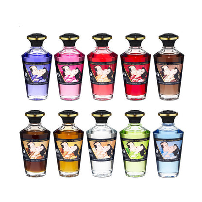A collection of ten Shunga Aphrodisiac Warming Oil bottles in various colors and flavors, each featuring traditional Japanese Shunga erotic art on the labels.