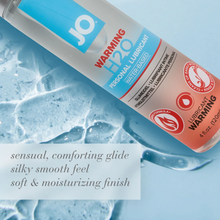 Load image into Gallery viewer, JO Warming H2O Personal Lubricant Water-Based 4 fl oz (120 ml) bottle laying on its back with the lubricant spilled out beside it (Showing the texture). In bottom left corner are product features: sensual, comforting glide; silky smooth feel; soft &amp; moisturizing finish.