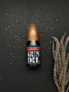 Gun Oil Silicone Lubricant 237 ml / 8 oz bottle with black glittery background with a tree branch on the bottom right.