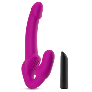 blush Temptasia Estella Strapless Dildo standing on its base, with the bullet vibe standing on its charging port beside.
