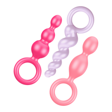 Load image into Gallery viewer, Satisfyer Booty Call Plugs Coloured variant, placed flat diagonally. Top to Bottom one pink plug, upside down light purple plug, and a light pink plug.