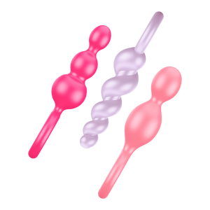 Satisfyer Booty Call Plugs Coloured variant side view, placed diagonally. Top to Bottom one pink plug, upside down light purple plug, and a light pink plug.