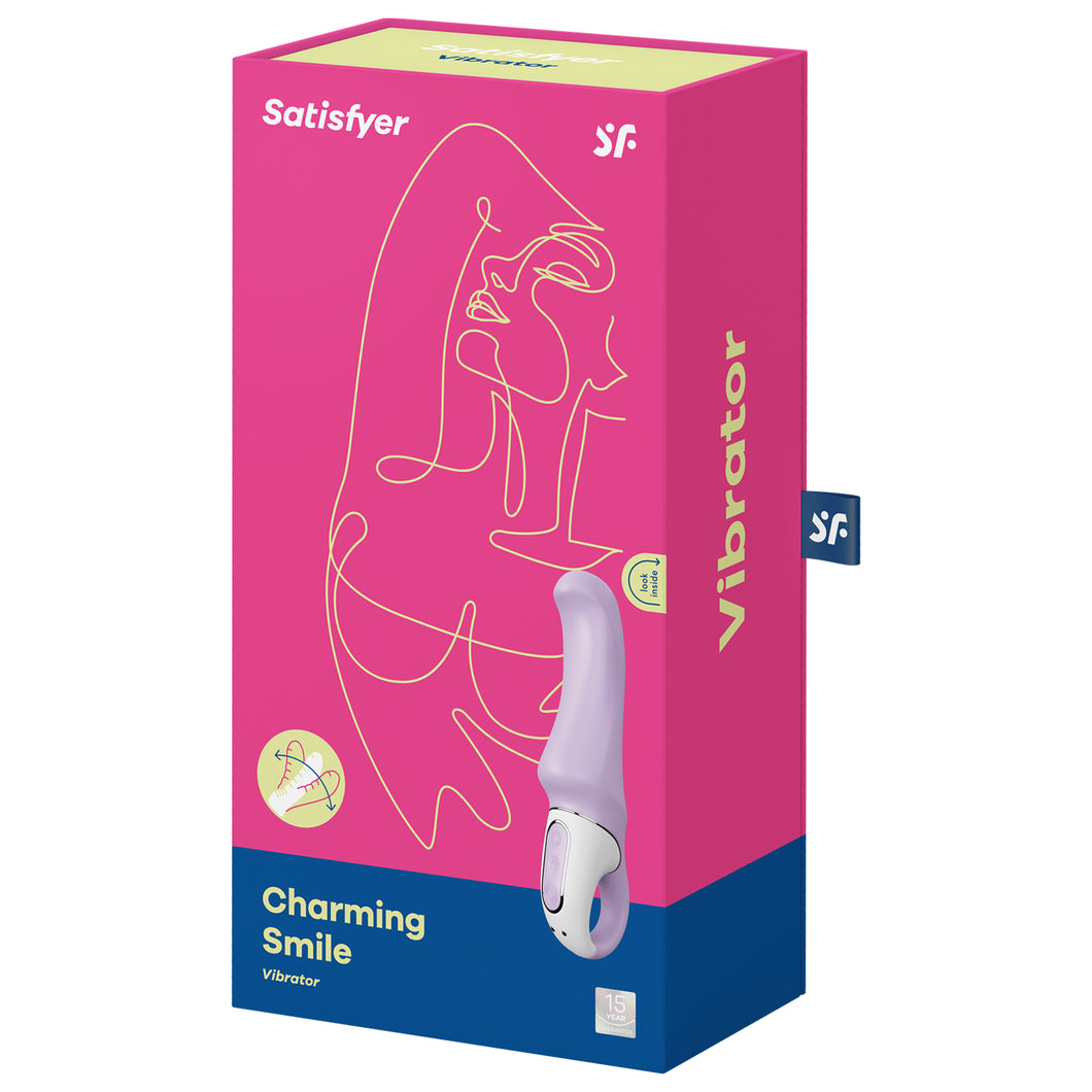 Front of the package from the top are the Satisfyer logos, on the lower left is an icon Silicone Flex, and below is the name of the product Charming Smile Vibrator. On the right side is the product facing front side with the controls visible on the left side of the handle, and a 15 year guarantee mark on the bottom right corner. On the right side of the package is written Vibrator, and a tag iis sticking out from the back with the SF logo.