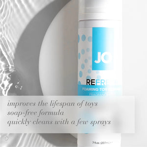 Laying in the background is a bottle of JO Refresh Foaming Toy Cleaner 7 fl. oz. (207 mL). Improves the lifespan of toys, soap-free formula, quickly cleans with a few sprays.
